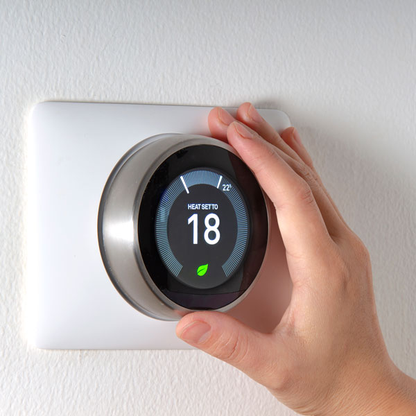 person adjusting smart thermostat
